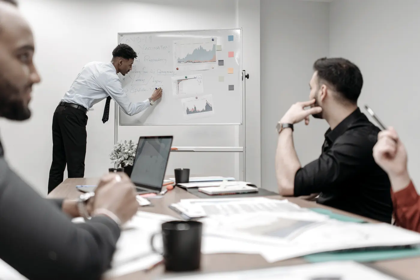 A working session at a whiteboard, with laptops and papers open on the table.